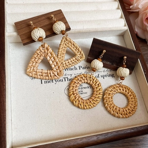 Detail of bohemian woven geometric earrings with wood beads and gold metal ear hooks
