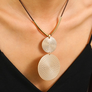 Textured double gold disc pendant necklace with brown cord chain worn by a woman