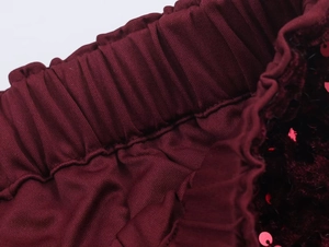 Detail of wine red elastic waistband with sequins and pleated fabric on pants