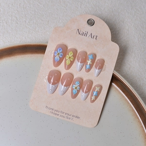 Detail of almond nude press-on nails with 3D floral carving and clear water drop accents