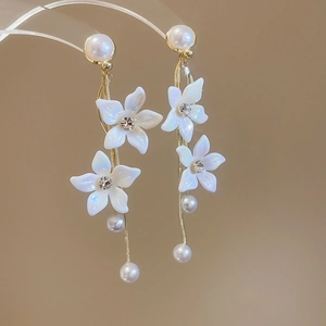 Macro detail of gold-plated flower earrings with white pearls and sparkling diamond accents