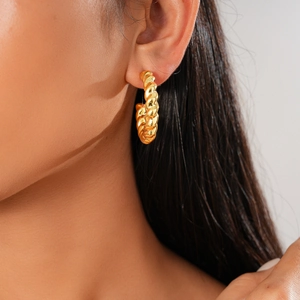 Detailed close-up of a model wearing a textured golden twisted hoop earring in a refined style