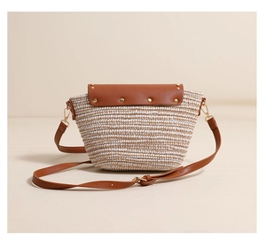Close-up of woven straw texture with brown leather flap and golden rivet studs