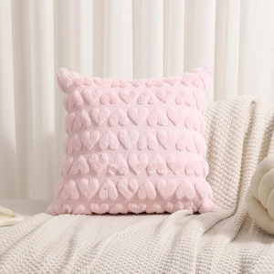 Close-up of pink plush pillow cover featuring raised heart patterns on a soft fabric