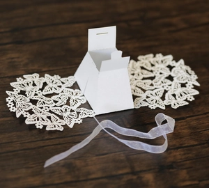 Detail of white laser-cut butterfly candy box with elegant decorative silk ribbon