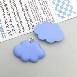 Detail shot of two blue cloud-shaped resin charms with metal rings for DIY jewelry