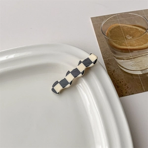Detail of wavy checkerboard hair clip on ceramic plate with a polished resin finish