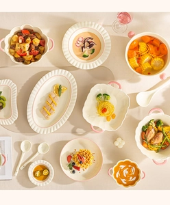 Nahaufnahme von cremefarbenem Keramikgeschirr mit rosa Wellenrand und eleganter Streifenstruktur