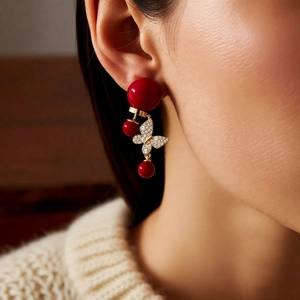 Détail de boucles d'oreilles papillon plaquées or 18 carats avec perles rouges sur modèle