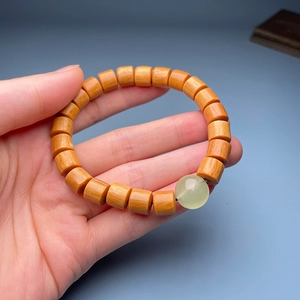 Macro detail of sandalwood beads with green jade bead on a natural wooden bracelet