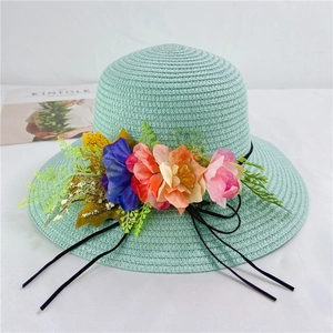 Detail of mint green straw sun hat decorated with colorful floral accents and black ribbon