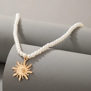 Detailed shot of elegant pearl necklace with a gold vintage sunburst pendant