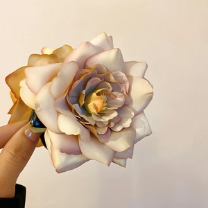 Vue détaillée d'une pince à cheveux rose en tissu champagne avec pétales dégradés