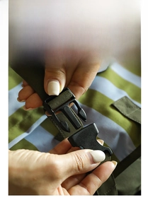 Detail of durable black plastic buckle with striped woven strap for travel organizers