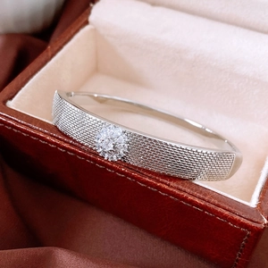 Detailed view of silver braided texture bracelet with floral zircon inlay in a leather box