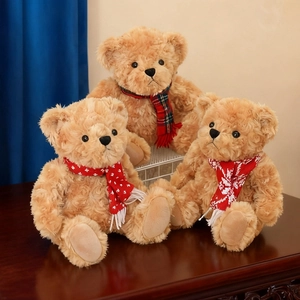 Three sizes of plush teddy bears with colorful scarves on a wooden table in a home setting