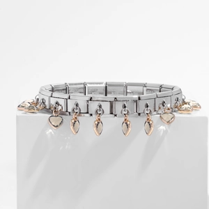 Macro detail of Italian charm bracelet featuring stainless steel links and rose gold heart charms