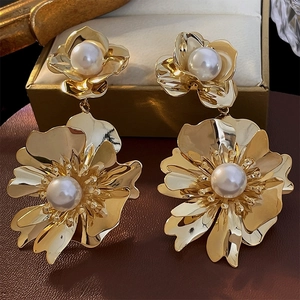 Boucles d'oreilles fleurs dorées avec perles sur un support en cuir luxe marron