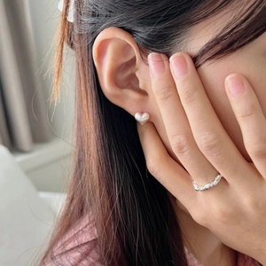 Close-up of heart-shaped pearl stud earrings and a silver twisted rope style ring