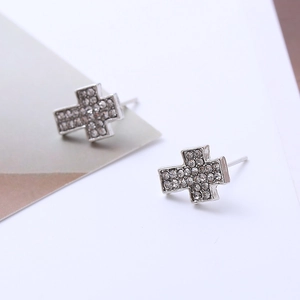 Macro shot of silver cross earrings with pavé-set rhinestones and geometric design