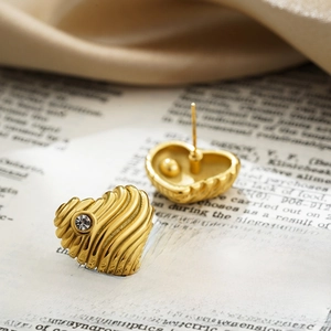 Textured 18K gold heart stud earrings with sparkling zircon on vintage paper background