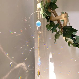 Detail showing crystal suncatcher creating rainbow light reflections on a white wall