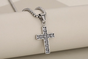 Detail of silver stainless steel cross pendant with crystal rhinestones on a display