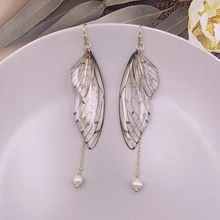 Detail of butterfly wing earrings with white pearls on a decorative ceramic plate