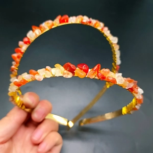 Detail of handmade gold metal headbands with orange and red polished crystal stones