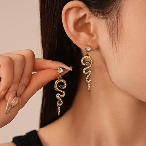 Detailed close-up of vintage gold snake drop earrings with shimmering crystals on model