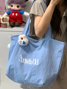 Detail of light blue drawstring tote bag with white rabbit plush charm and logo