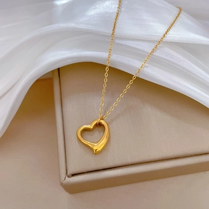 Detailed close-up of gold titanium steel heart pendant necklace on an elegant jewelry box