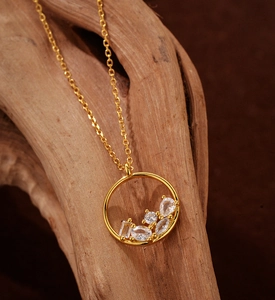 Detail of a gold circular openwork pendant featuring mixed-cut cubic zirconia on a chain