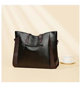 Close-up of black PU leather tote bag with brown straps and back zipper pocket