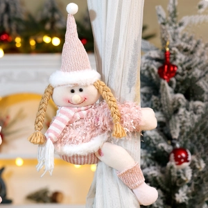 Detail of pink knitted Christmas elf doll curtain tieback with cozy fireplace background