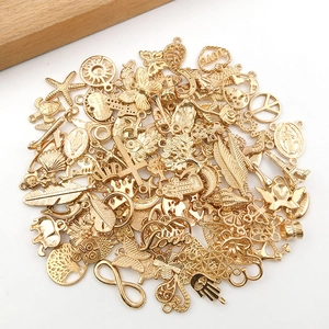 Macro detail of assorted gold alloy charms featuring butterfly and heart shapes for DIY jewelry
