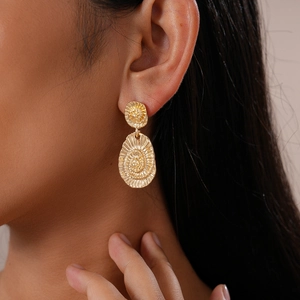Gros plan de boucles d'oreilles dorées géométriques avec texture en spirale