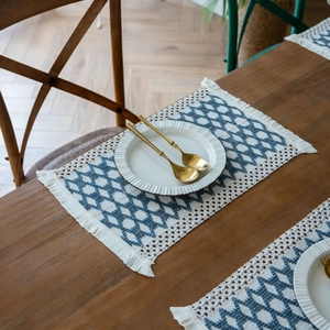 Navy blue diamond weave cotton placemat with bohemian fringe on a wooden table