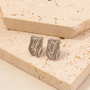 Detailed macro view of 304 stainless steel silver geometric bow earrings on stone