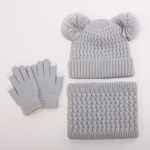Detail of grey cable knit winter set featuring dual pom pom beanie and touchscreen gloves