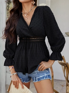 Détail d'une tunique noire à pois avec col en V et taille nouée pour un look de loisirs