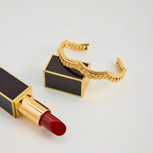 Spitzen-Hohlwellen-Armreif aus 18K vergoldetem Edelstahl neben Lippenstift als Maßstab