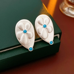 Detailed view of vintage silver drop earrings with floral relief and turquoise stones