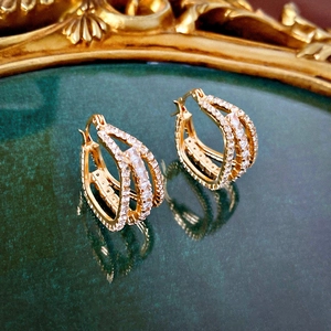 Macro view of multi-layered gold geometric hoop earrings with shimmering cubic zirconia