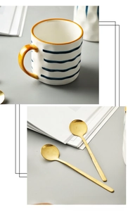Detail view of large ceramic mug with blue stripes and two gold mixing spoons
