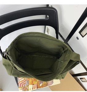 Detail of army green canvas tote bag featuring top zipper and interior pocket for storage