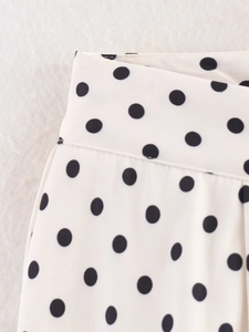Détail du pantalon blanc à pois noirs avec coutures de taille précises et nettes