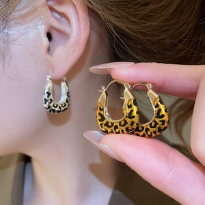 Detail of vintage leopard print square drop earrings in gold and silver finish on model