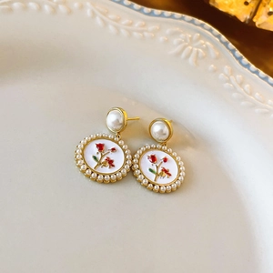 Detailed macro view of vintage gold flower earrings with pearls and red rose enamel