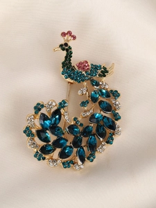 Detailed shot of peacock brooch with colorful crystals on beige silk background